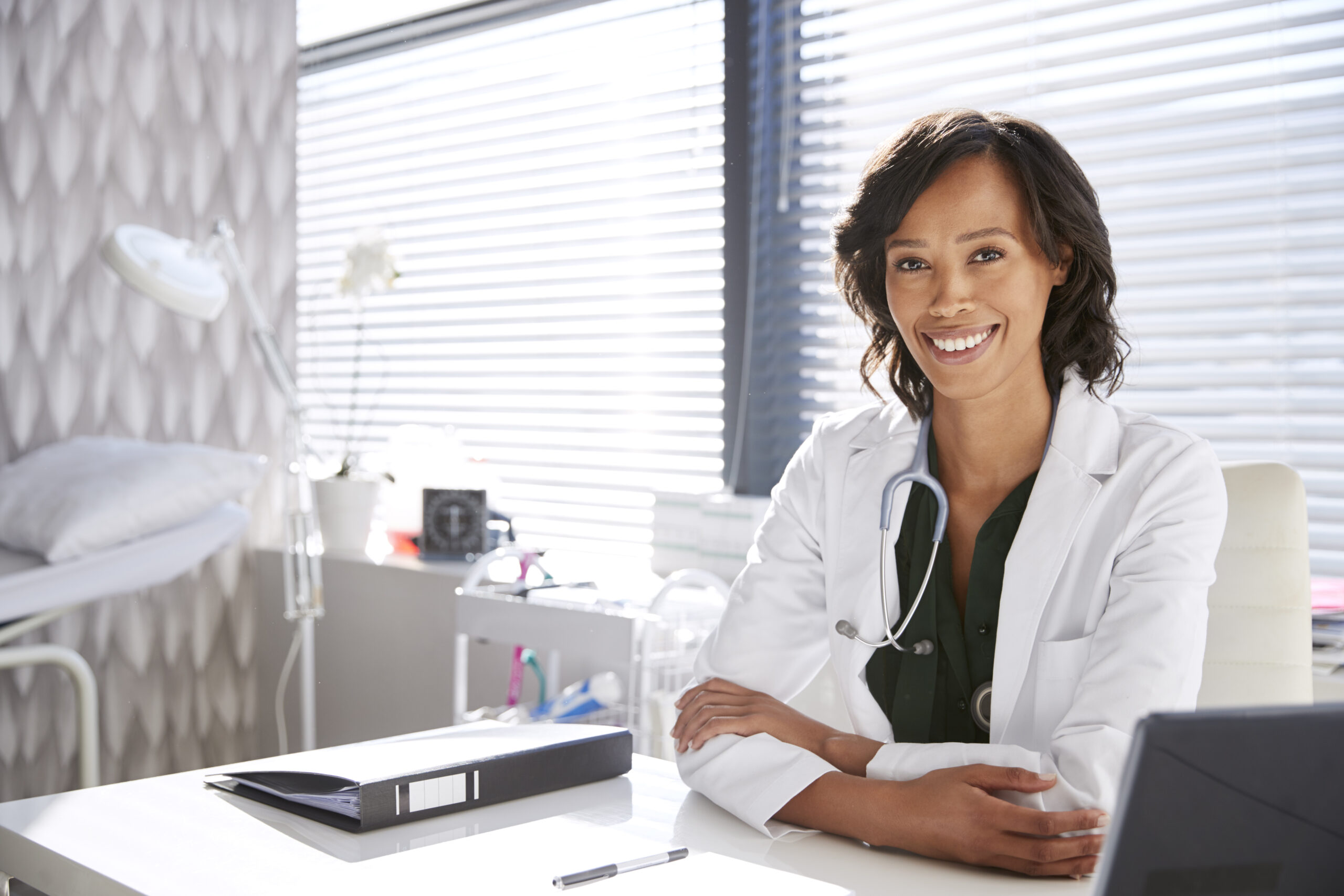 Portrait of smiling female plastic surgeon wearing white coat with stethoscope